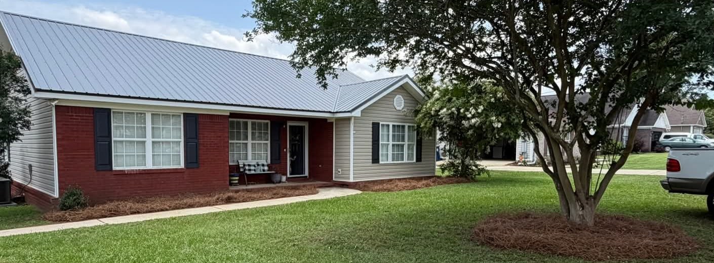 Brick house with fresh pine straw beds and a pine straw tree ring
