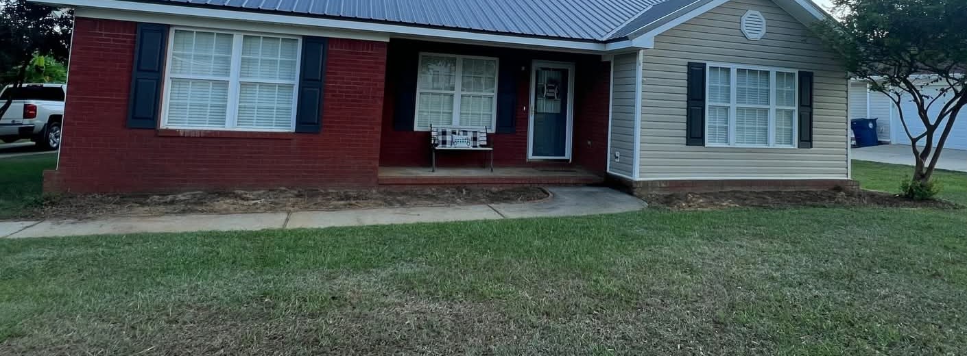 Before: bare dirt beds along a brick house